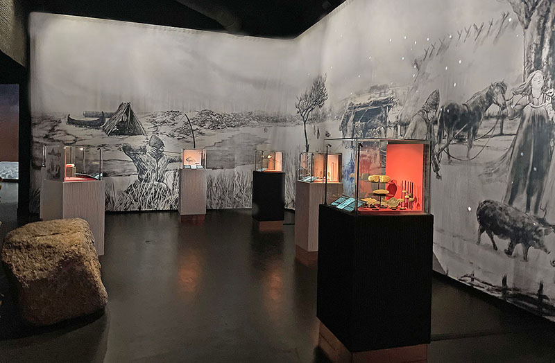 Displays of archaeological artifacts and an illustration on the wall depicting what the settlement may have looked like before the fortress was built.