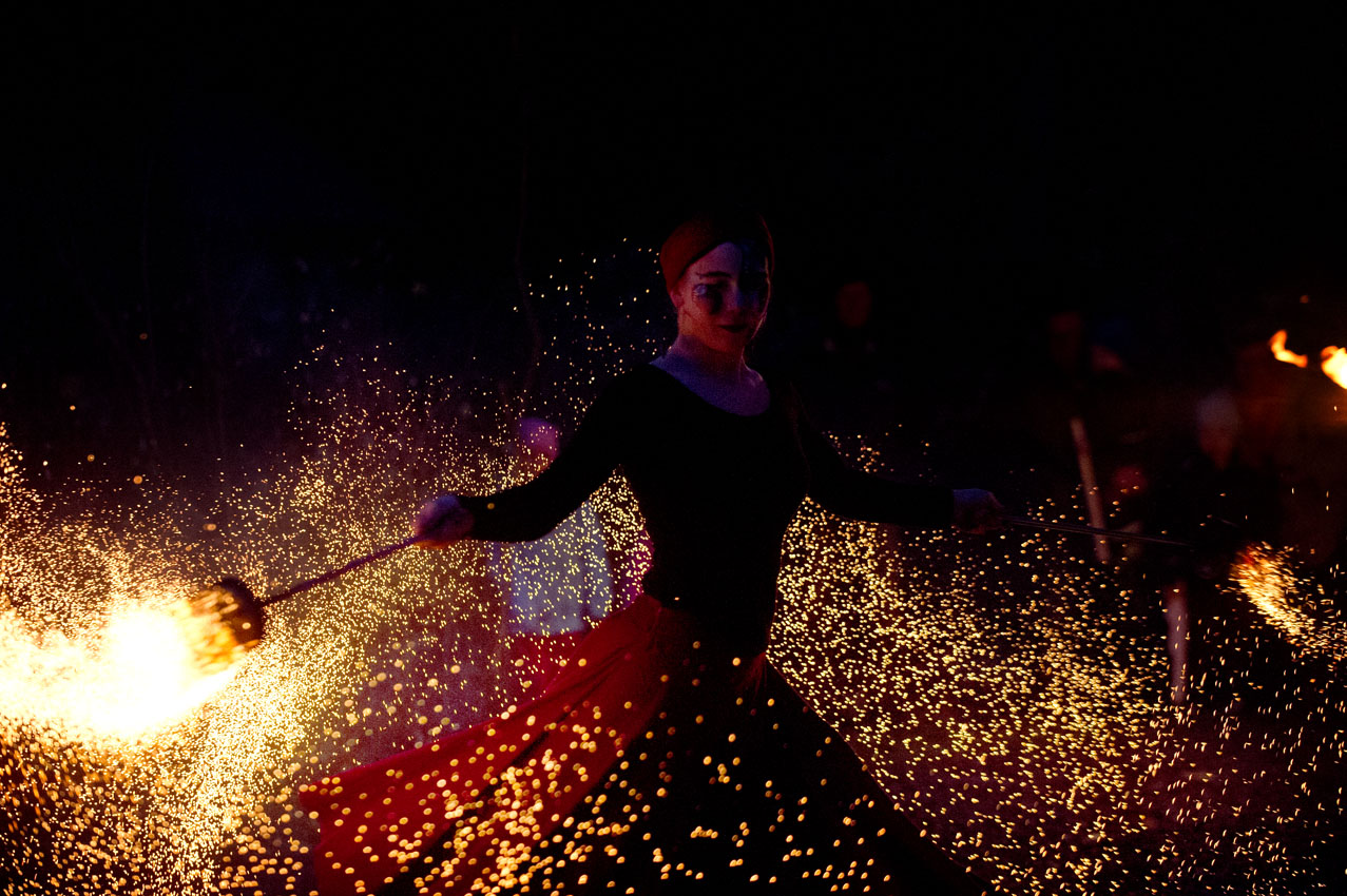 Eldshow. Kvinna snurrar två eldkar i luften.