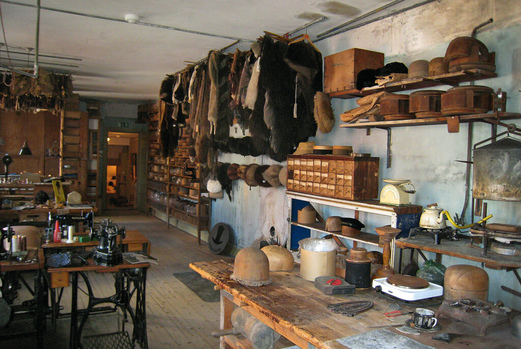 Hattmuseet på Algatan 35 i Trelleborg. I rummet ser man symaskiner, hattstockar, pälsar och ett stort arbetsbord.
