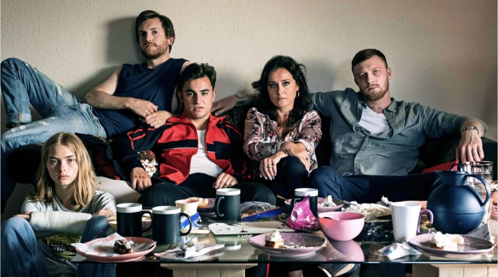 Bild från filmen Wildland. En familj sitter i en soffa. På bordet framför dem ser man att de har ätit tårta.