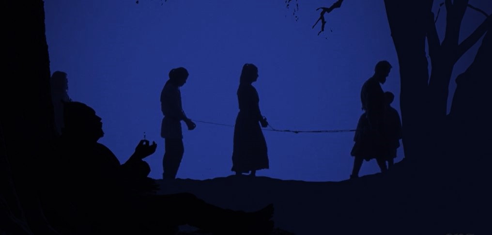 Stillbild från film som visas på Trelleborgen. Svarta silhuetter av trälar mot mörkt blå bakgrund