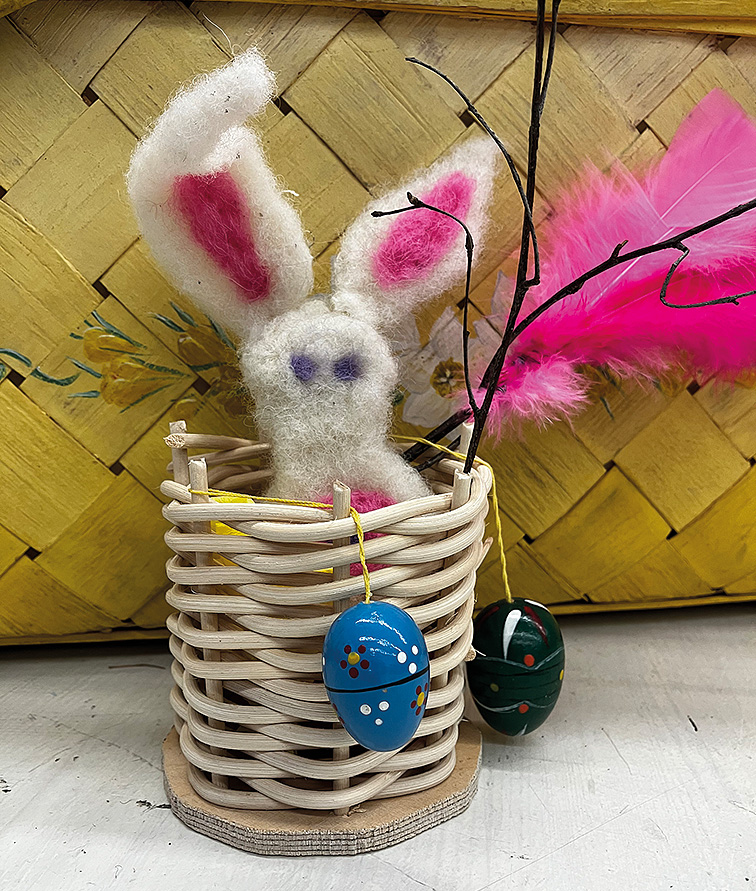 Liten korg med en tovad kanin och några påskägg.
