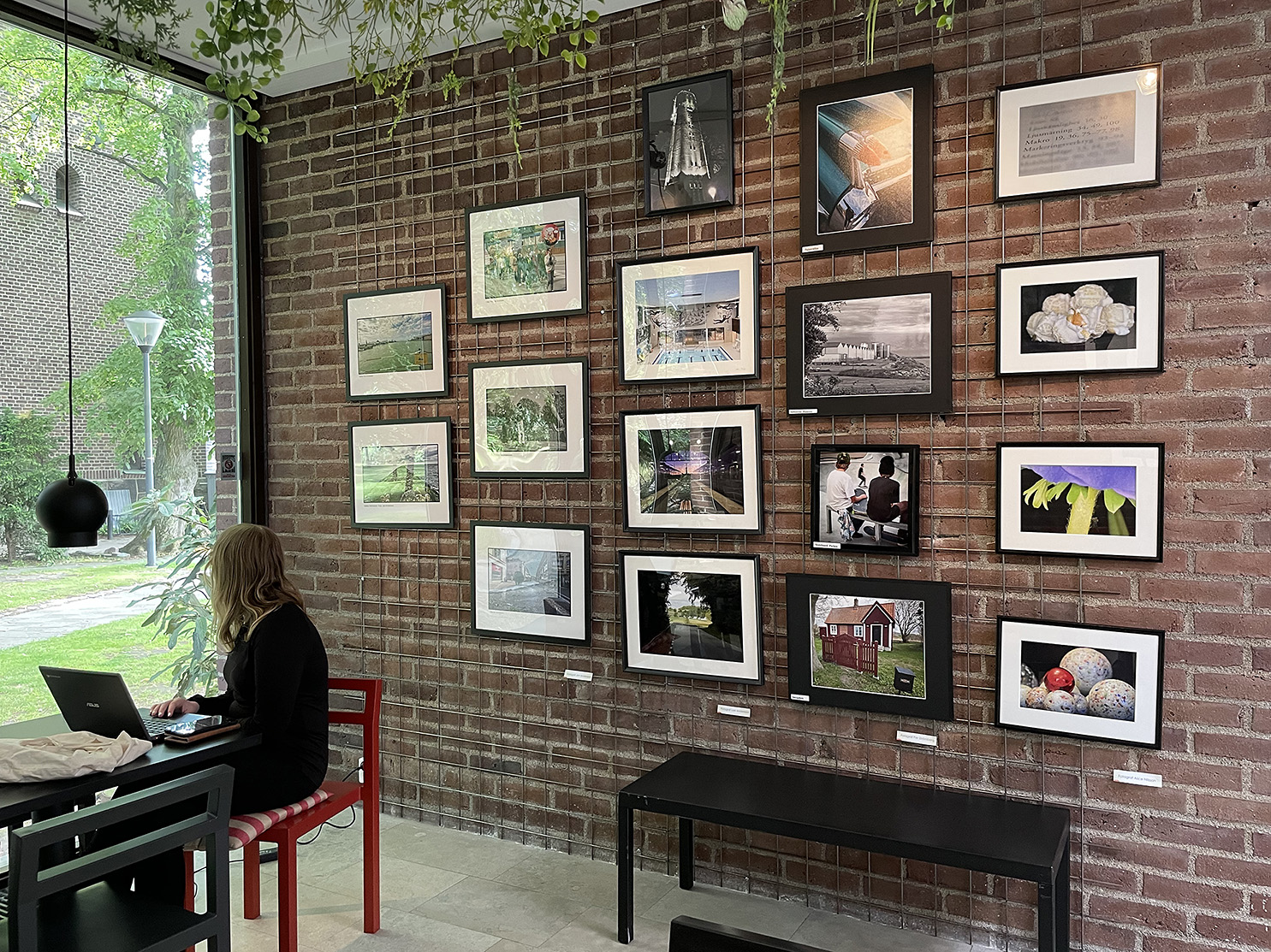 Fotografier från Trelleborgs fotoklubb hänger på en tegelvägg på Trelleborgs Museum