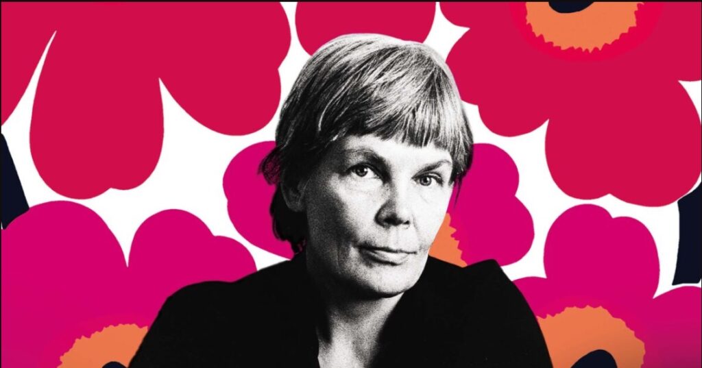 Bakom mönstren: Ett porträtt av Maija Isola. Ett ansikte med en bakgrund av ett tyg med stora rosa blommor.