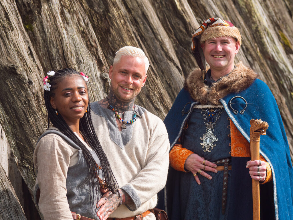 Vikingatida bröllop. Ett gift par och en vigselförrättare, alla i vikingatida kläder, framför Trelleborgen