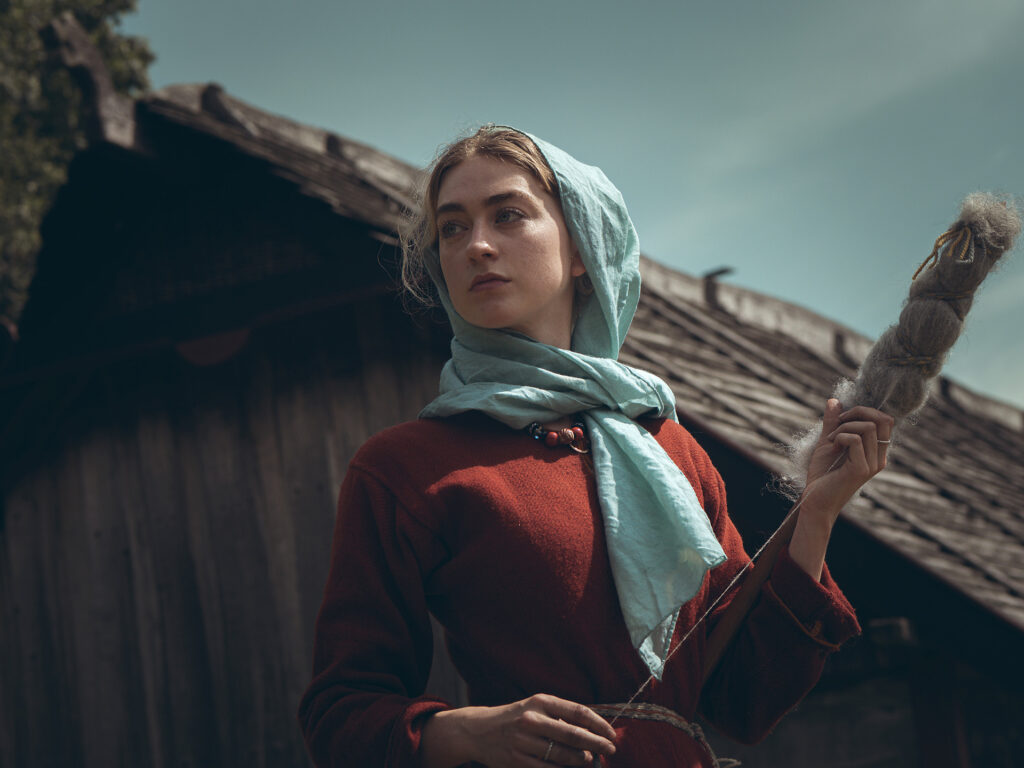 Kvinna i vikingatida kläder spinner tråd.